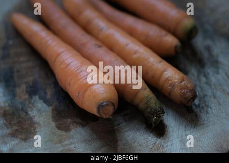 Die gewaschenen Karotten, die aus dem Garten aufgenommen wurden, legen auf die hölzerne Oberfläche. Tageslicht, Draufsicht. Stockfoto
