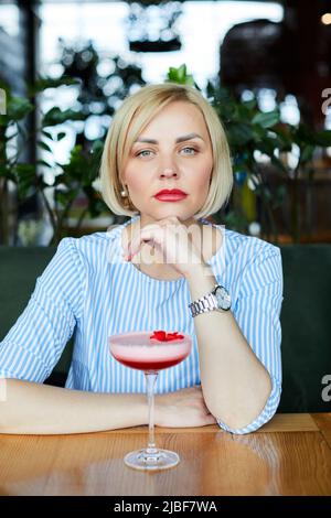 Porträt einer attraktiven jungen Frau, die einen Cocktail in einem Café trinkt Stockfoto