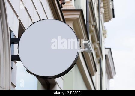 Blank Metall Kreis Geschäft Schild auf Straße an der Wand montiert hängen. Leeres Plastiktafel-Modell. Stockfoto