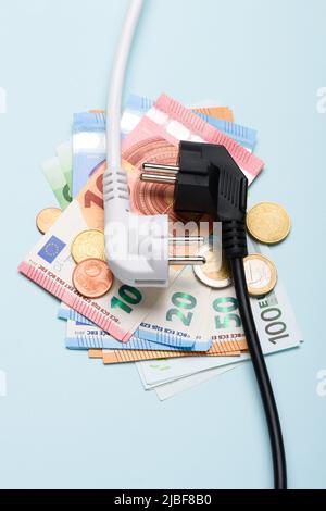 Elektrische Steckdosen auf Euro-Banknoten auf blauem Hintergrund. Konzept teurer Stromkosten und steigender Energiebillimpreise. Stockfoto