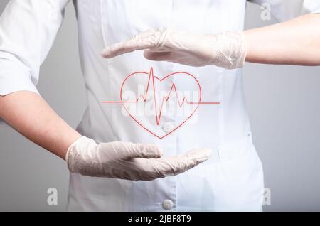 EKG-Konzept. Arzt hält Herz mit Herzrhythmusstörungen zwischen den Händen in Handschuhen. Elektrokardiogramm-Test wird durchgeführt. Herzkrankheit, Angriffserkennung. Hochwertige Fotos Stockfoto