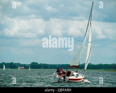 Segelboot, das an einem windigen, sonnigen Sommertag auf einem See segelt Stockfoto