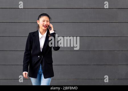 Glückliche asiatische Geschäftsfrau, die am Telefon spricht Stockfoto