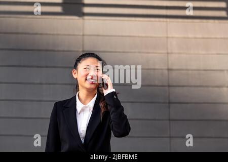 Lächelnde asiatische Geschäftsfrau, die am Telefon spricht Stockfoto