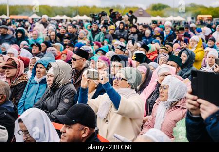 Bolgar, Tatarstan, Russland. 21.Mai 2022. Das Publikum beim Weihnachtskonzert. Eine Frau, die auf dem Smartphone ein Konzert schießt. Leute, die ein Konzert im Park unter freiem Himmel beobachten Stockfoto