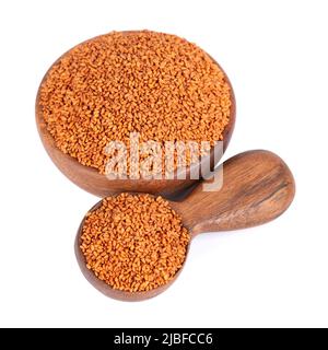 Camelina sativa Samen in Holzschale und Löffel, isoliert auf weißem Hintergrund. Samen von Kamelina oder Falschflachs. Rohstoff für Kamelinaöl Stockfoto