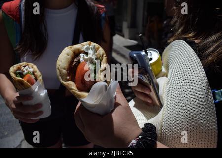 Athen, Griechenland. 4.. Juni 2022. Zwei Frauen halten das traditionelle Street Food „Souvlaki“, das sie gerade von einem Restaurant gekauft haben. Der Preis für Griechenlands beliebtestes Street Food steigt in die Höhe, da die Inflation im Mai von 10,2 Prozent im April auf rund 10,7 Prozent gestiegen ist und damit den höchsten Stand seit 28 Jahren erreicht hat. (Bild: © Dimitris Aspiotis/Pacific Press über ZUMA Press Wire) Stockfoto