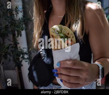 Athen, Griechenland. 4.. Juni 2022. Eine Frau hält das traditionelle Street Food „Souvlaki“, das sie gerade von einem Restaurant gekauft hat. Der Preis für Griechenlands beliebtestes Street Food steigt in die Höhe, da die Inflation im Mai von 10,2 Prozent im April auf rund 10,7 Prozent gestiegen ist und damit den höchsten Stand seit 28 Jahren erreicht hat. (Bild: © Dimitris Aspiotis/Pacific Press über ZUMA Press Wire) Stockfoto