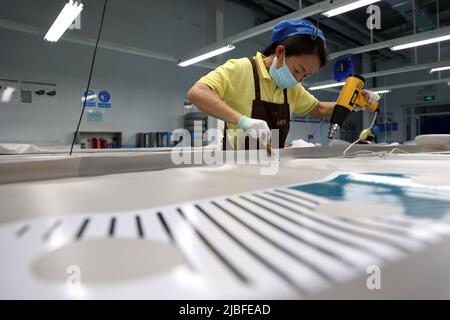 BINZHOU, CHINA - 6. JUNI 2022 - Ein Arbeiter produziert Surfbretter für Bestellungen aus dem Ausland in einer Surfbrett-Produktionswerkstatt in Binzhou, Shandong, Ostchina Stockfoto