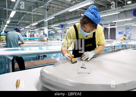 BINZHOU, CHINA - 6. JUNI 2022 - Ein Arbeiter produziert Surfbretter für Bestellungen aus dem Ausland in einer Surfbrett-Produktionswerkstatt in Binzhou, Shandong, Ostchina Stockfoto