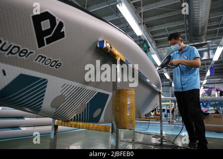 BINZHOU, CHINA - 6. JUNI 2022 - Ein Arbeiter produziert Surfbretter für Bestellungen aus dem Ausland in einer Surfbrett-Produktionswerkstatt in Binzhou, Shandong, Ostchina Stockfoto