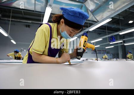 BINZHOU, CHINA - 6. JUNI 2022 - Ein Arbeiter produziert Surfbretter für Bestellungen aus dem Ausland in einer Surfbrett-Produktionswerkstatt in Binzhou, Shandong, Ostchina Stockfoto