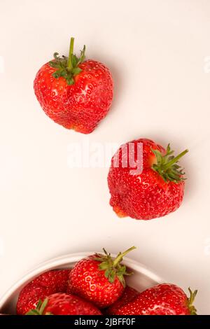 Erdbeeren auf weißem Hintergrund von oben. Zwei rote Beeren und Erdbeeren auf einem Teller Stockfoto