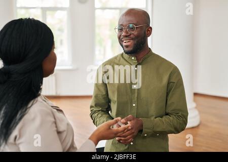 Glückliche junge afroamerikanische Psychologin, die weibliche Patientin konsultiert und ihre Sorgen und Probleme während der Psychotherapiesitzung teilt Stockfoto