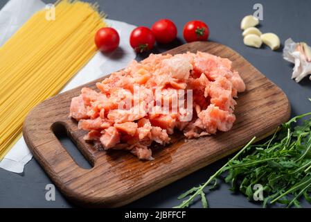 Kochen von Spaghetti mit Lachs und Gemüse. Die Rohstoffe liegen auf einem grauen Hintergrund. Stockfoto