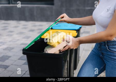Die mittlere Auswahl der Weibchen hält zwei Papptablett mit Eiern. Müll, Eierkarton und Verfärbung in Recyclingbehälter. Nahaufnahme einer Frau, die blau steht Stockfoto