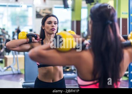 Fitness-Frau macht Übung mit einem Wasserkocher Glocke. Stockfoto