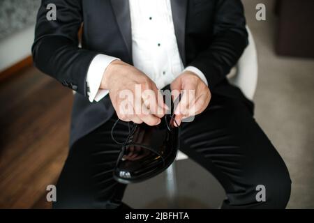 Der Bräutigam fixiert die Schnürsenkel an seinen Schuhen. Stockfoto