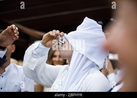 Bei einer Hochzeit trinkende Gäste mit verbundenen Augen Alkohol. Stockfoto