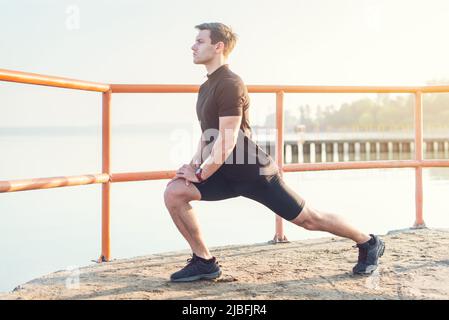 Fitness-Mann streckt seine Beinmuskeln im Freien Stockfoto