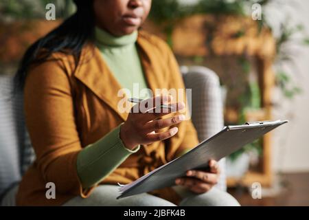 Hand einer jungen, selbstbewussten Psychologin mit Stift und Klemmbrett, die dem Patienten etwas erklärt oder während der Sitzung Ratschläge gibt Stockfoto