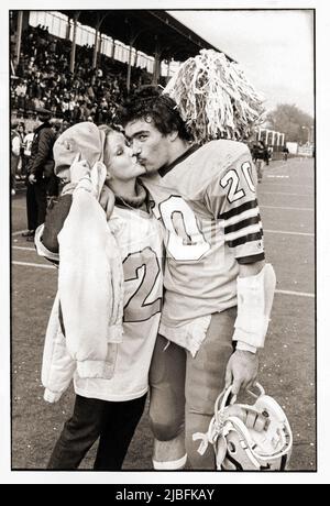 Nach einem Fußballsieg wird ein Fußballspieler der Canarsie High School von seiner Freundin, die eines seiner Trikots trägt, geküsst. 1982 in Brooklyn, NYC. Stockfoto