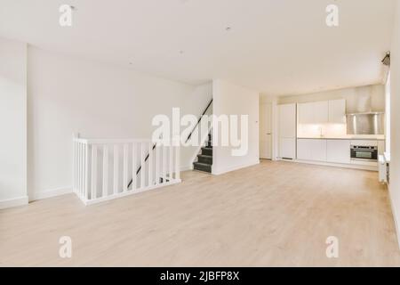 Theke mit weißen Schränken in heller, geräumiger Küche in moderner, leerer, offen gestaltetes, stilvoll renovierter Wohnung Stockfoto