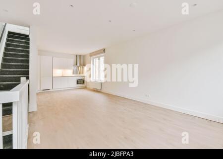 Theke mit weißen Schränken in heller, geräumiger Küche in moderner, leerer, offen gestaltetes, stilvoll renovierter Wohnung Stockfoto