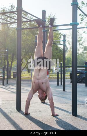 Junge fit muskulösen Mann tun Handstand Workout im Freien Stockfoto