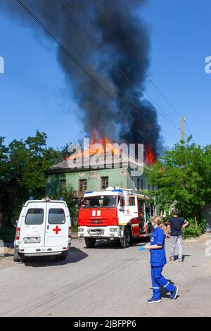 Russland, Rostov-on-Don - 2. Juni 2022: Feuerwehrleute sind gekommen, um einen Brand in einem verlassenen Haus zu löschen, ein Krankenwagen, Arzt und Zuschauer sind st Stockfoto