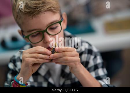 Ein Schüler in der Schule, der im Roboterunterricht mit Elektronikkomponenten arbeitet. Stockfoto