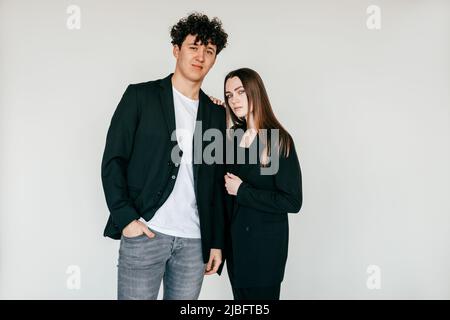 Porträt von jungen attraktiven dunkelhaarigen lockigen Mann und langhaarige Frau in schwarzem Outfit, Schleifen in der Nähe. Speicherplatz kopieren Stockfoto