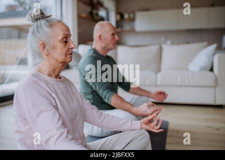 Ein Seniorenpaar macht zu Hause gemeinsam Entspannungsübungen. Stockfoto