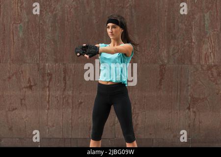 Weibliche Athletin, die ihren Arm streckt. Junge Frau macht Aufwärmübungen vor dem Laufen Stockfoto