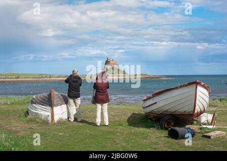 Urlaub in Großbritannien, Rückansicht eines reifen Paares im Urlaub auf Holy Island mit Blick über den Hafen nach Lindisfarne Castle, Northumberland, England, Großbritannien Stockfoto