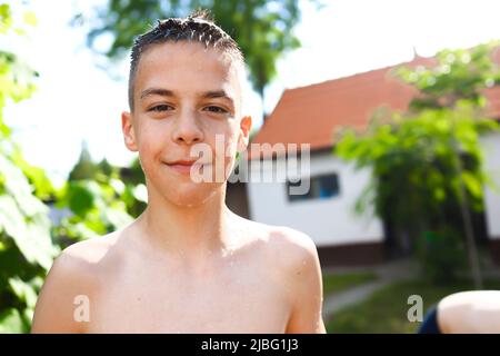 Porträt eines nassen jungen Jugendlichen, der während der Sommerferien Spaß hat Stockfoto