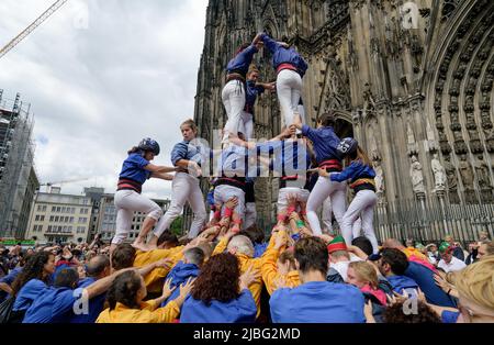 Köln, Deutschland. 06.. Juni 2022. Rund 180 Mitglieder der Vereinigung der Castellers de la Vila de Gracia in Barcelona bauen vor dem Kölner Dom einen katalanischen Turm. Die Castells (menschliche Türme) sind ein UNESCO-Weltkulturerbe. Quelle: Henning Kaiser/dpa/Alamy Live News Stockfoto