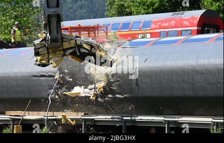 Garmisch Partenkirchen, Deutschland. 06.. Juni 2022. Ein Bagger trennt einen Wagen zur Demontage in zwei Teile. Drei Tage nach dem Zugunfall in Garmisch-Partenkirchen gehen die Sanierungsarbeiten voran. Quelle: Angelika Warmuth/dpa/Alamy Live News Stockfoto