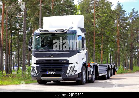 Neuer, weißer Volvo FMX-LKW vor dem Transportanhänger für Forstfahrzeuge, der auf dem Asphalthof geparkt ist. Raasepori, Finnland. 26.Mai 2022. Stockfoto