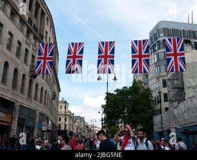Union Jack hängend über die Charing Cross Road, während sich die Massen zerstreuen, nach dem Ende der Vorbeiflug, um die Parade von Trooping the Color: The Queen’s Birthday zu feiern, die Teil ihrer Platinum Jubilee Celebrations 2022 ist Stockfoto