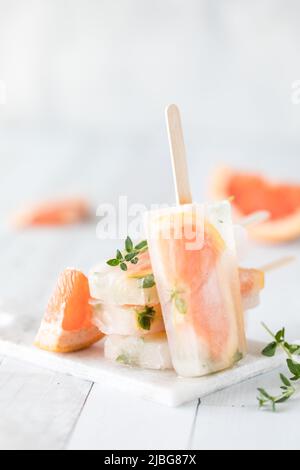 Ein Grapefruit-Thymian-Eis, das sich an einen Stapel derselben Eiszapfen lehnt. Stockfoto