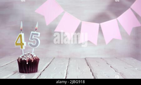 Geburtstagsnummer. Festlicher Hintergrund für ein Mädchen oder eine Frau mit einem Muffin und Kerzen brennend rosa in Pastellfarben mit Dekorationen für jeden Urlaub, Stockfoto