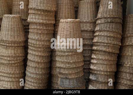 Viele braune gewebte Körbe aus natürlichem Rattan. Stapel von natürlichen Rattan Körben werden angezeigt, Handmade Thai Kunsthandwerk. Selektiver Fokus. Stockfoto