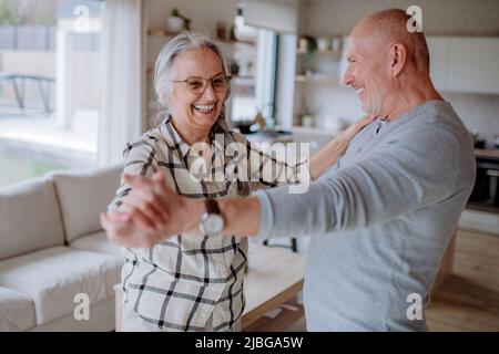 Fröhliches Seniorenpaar, das zu Hause zusammen tanzt. Stockfoto