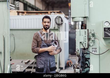 Porträt eines Schweißertechnikers, der in der Nähe der Metallmaschine in der Industriefabrik steht. Stockfoto