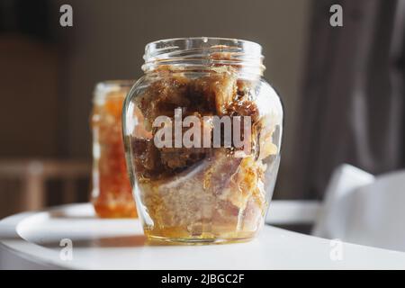 Offene Glasgefäße gefüllt mit frischem Honig in Bienenwachs auf weißem Tisch horizontal Stockfoto