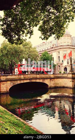 Rote Doppeldecker-Stadtrundfahrt 'Hop on / Hop off'-Bus auf einer Brücke über den Kö-Graben, den Stadtkanal an der Königsallee in Düsseldorf/Deutschland. Stockfoto