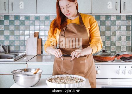 Junge Frau kocht in der heimischen Küche und fotografiert Lebensmittel für soziale Medien. Blogger schreibt einen kulinarischen Blog. Lifestyle, Home-Leisure-Konzept. Stockfoto