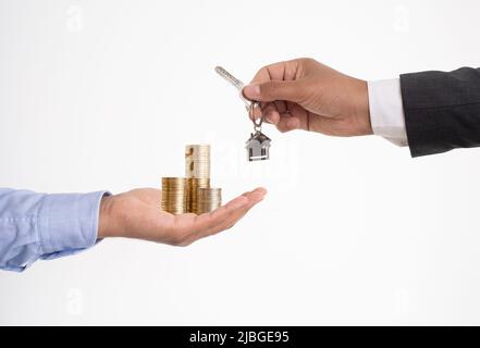 Nahaufnahme des Geldwechsels der Hände und des Hausschlüssels auf isoliertem Hintergrund. Stockfoto