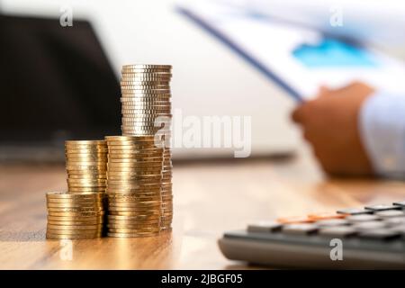Nahaufnahme des Münzstapels, der Karten und Statistiken mit dem Taschenrechner. Konzept der Rechnungslegung, Budget und Gewinn. Stockfoto